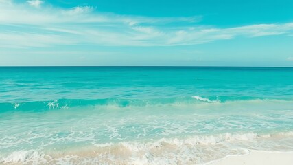 A pristine turquoise ocean meets a tranquil white sandy beach under a vibrant blue sky perfect for summer vacations.