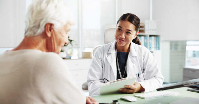 Senior woman, happy doctor and consultation with clipboard for healthcare report, symptoms or checkup. Medical professional, appointment and talking to patient for help or writing results in hospital