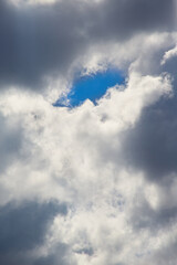 A gap in the shape of an eye among the clouds reveals a blue sky, an eye in the sky. Used in...