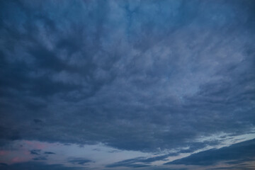 A wide landscape with gloomy dark clouds and crimson highlights on the horizon—a harbinger of...