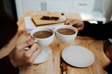 Young adults enjoy coffee and conversation at a cozy café, sharing laughter, bonding, and relaxation in a warm, friendly atmosphere indoors.