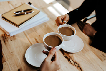 Young adults enjoy coffee and conversation at a cozy café, sharing laughter, bonding, and relaxation in a warm, friendly atmosphere indoors.