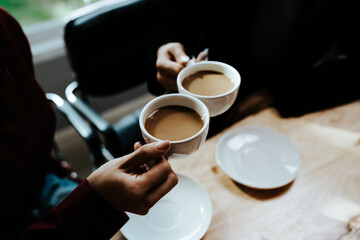 Young adults enjoy coffee and conversation at a cozy café, sharing laughter, bonding, and relaxation in a warm, friendly atmosphere indoors.