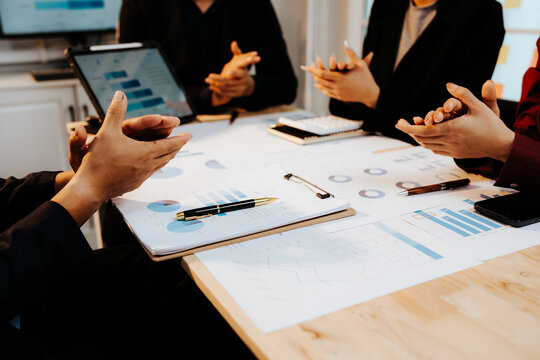 A group of professionals collaborates in an office, analyzing financial graphs and documents to strategize business growth and project success.