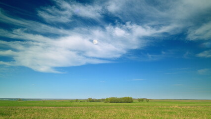 Obraz premium A vast expanse of open fields stretches beneath a clear blue sky adorned with wispy clouds