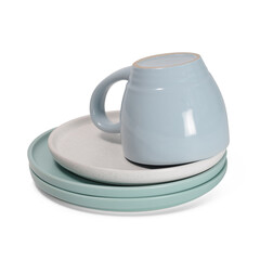 Stack of light green and beige plates with turned blue cup on it on white background