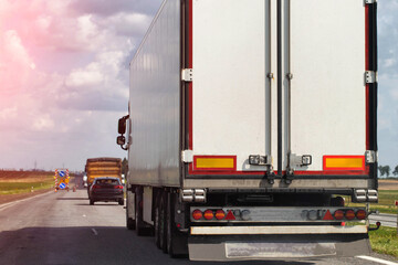 A truck with a semi-trailer delivers cargo along the highway to the marketplace. Delivery service from an online store to the buyer. Copy space for text