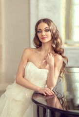Beautiful and sexy young woman in a white luxurious wedding dress. Preparation for the wedding, romantic morning of the bride. Girl with beautiful long hair