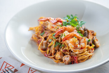 A plate of pasta with shrimp and mushrooms, garnished with fresh herbs.