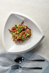 Close-up of a plate of stir-fried meat with red chilies and herbs.