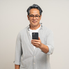 Handsome asian mature old man standing using smartphone on isolated white background. Happy Portrait of cheerful smiling senior asian man holding cell phone. Mature People and lifestyle