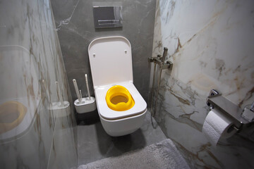 Yellow child toilet seat for children in the toilet. Convenience and comfort for the child on the toilet, close-up