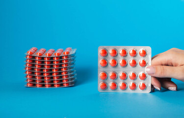 Red pills in hand on blue background. Concept of antidepressants and antioxidants in medicine. Copy space for text