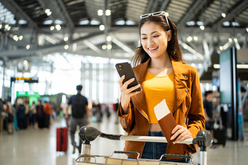 happy young asian woman traveler holding boarding pass ticket, passport and smartphone at the...