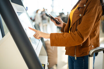 Plakat Close up the woman hands touching the screen while self check in kiosk technology machine getting boarding pass at the airport terminal