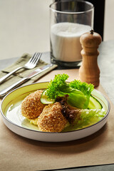 Breaded chicken kiev cutlets served on plate with mashed potatoes, fresh cucumber and lettuce