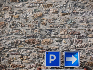 parking sign showing the directing towards a public parking lot in front of a vintage brick wall