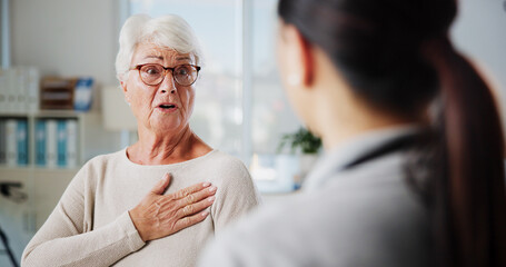 Obraz premium Discussion, chest pain and healthcare with old woman and doctor for rehabilitation, heart arrhythmia or medical. Cardiologist, help and advice with people in clinic for healing and breathing exam