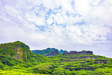 a hillside covered with green vegetation, interspersed with the ruins of several abandoned copper...