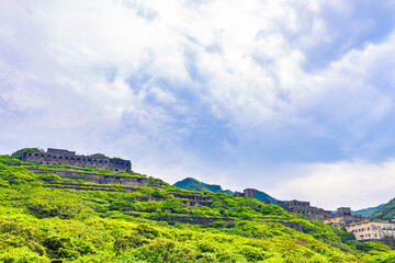 a hillside covered with green vegetation, interspersed with the ruins of several abandoned copper...
