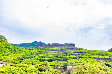 a hillside covered with green vegetation, interspersed with the ruins of several abandoned copper...