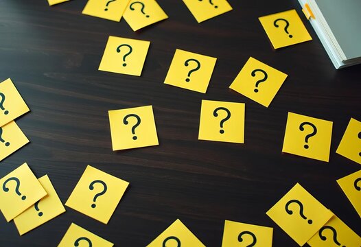 Many question marks on yellow sticky notes scattered on a dark wooden desk,   task,   workspace