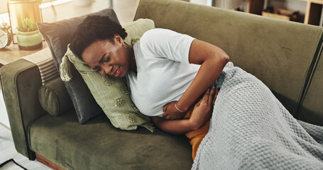 Black woman, pain and stomach cramps on sofa for virus, digestion problem and endometriosis....