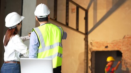 Two architects or civil engineers visiting large construction site, looking at floor plans.