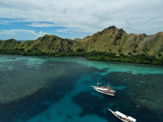 Aerial view A phinisi boat is sailing carrying tourists who will visit the islands around the waters of Labuan Bajo, East Nusa Tenggara, Indonesia.