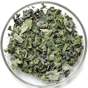 Dehydrated mullein leaves in a glass bowl on a seamless white surface