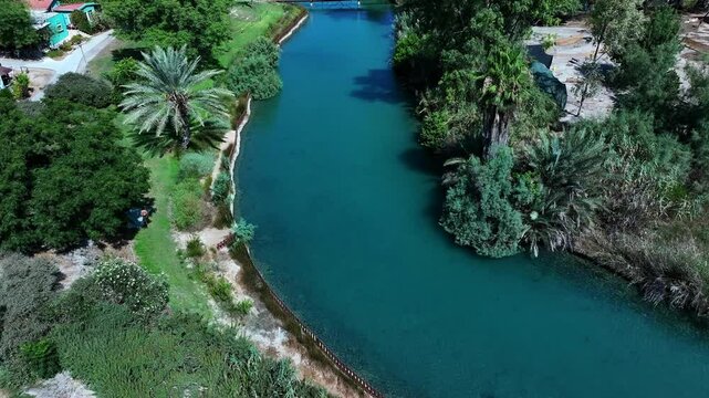 Aerial Tilt Down Shot Of Asi River Stream In Kibbutz Community, Drone Flying Backwards On Sunny Day - Nir David, Israel