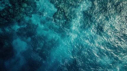 Obraz premium Aerial shot reveals ocean's varying turquoise hues and underwater rock formations. Use as a backdrop for travel, environmental or nature themes visually.