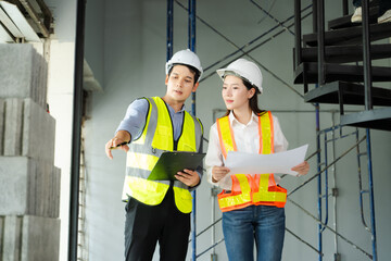 Architects and engineers discuss construction project using blueprints and tech tools. Teamwork, planning