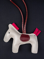 Close up cute leather gray horse keychain with saddle for bag on black background