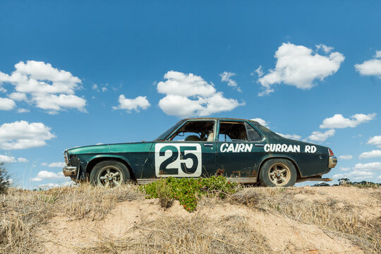 An old car sitting up on a mound of dirt against a blue sky