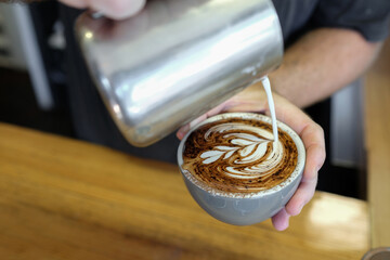 Barista pouring milk to make coffee cappuccino art