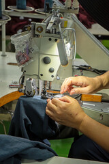 hand with sewing machine in clothing factory, textile and industry concept.