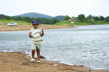 During a bright summer vacation, the girl enjoyed a walk on the sandy beach by the reservoir on the mountain.