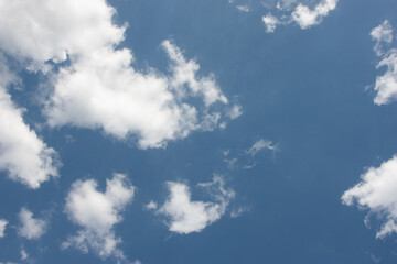 Snowy white and fluffy clouds in a bright blue sky with an empty place. A template for the design with copy space. Clouds form interesting silhouettes and patterns.