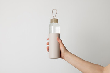 Woman's hand holding reusable eco-friendly bottle with fresh water in it. Healthy lifestyle, bottle mock up, copy space for your brand.