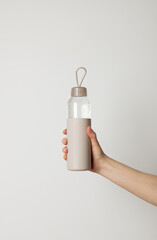 Woman's hand holding reusable eco-friendly bottle with fresh water in it. Healthy lifestyle, bottle mock up, copy space for your brand.