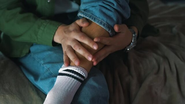 A man in blue jeans sits on the bed and massages his sore leg.
Pain in the leg from an injury.
Injured male leg.
Pain, fracture, sprain, dislocation, bruise