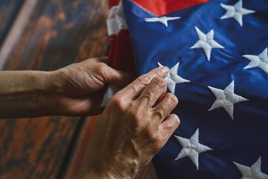 Hands folding American flag with care and precision