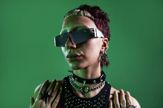 Futuristic cyberpunk woman in edgy clothing against green background