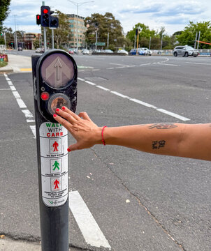 Hand pressing crosswalk button in Melbourne