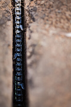 Trencher chain blade digging hole in dirt