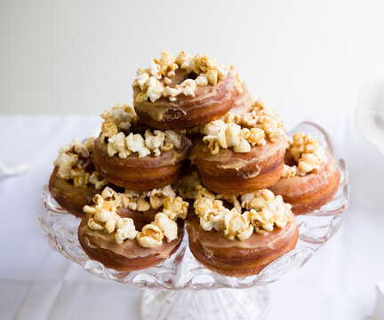 Cake stand filled with popcorn covered donuts