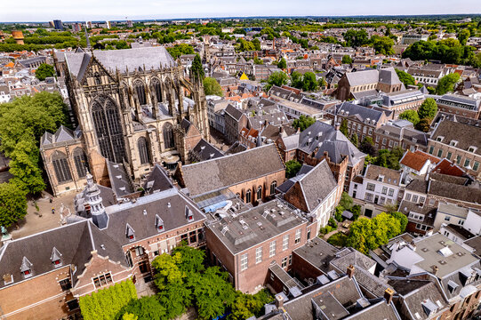 Gothic architecture of cathedral De Dom ambulatory with historic medieval buildings of University of Utrecht next to the rising facade