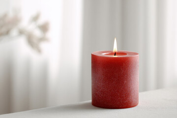 single red candle softly glowing against light background creating warm and inviting atmosphere