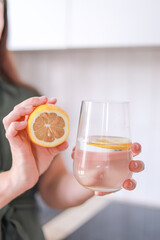 A woman shows a glass of lemon water drinking water with lemon helps strengthen the immune system...